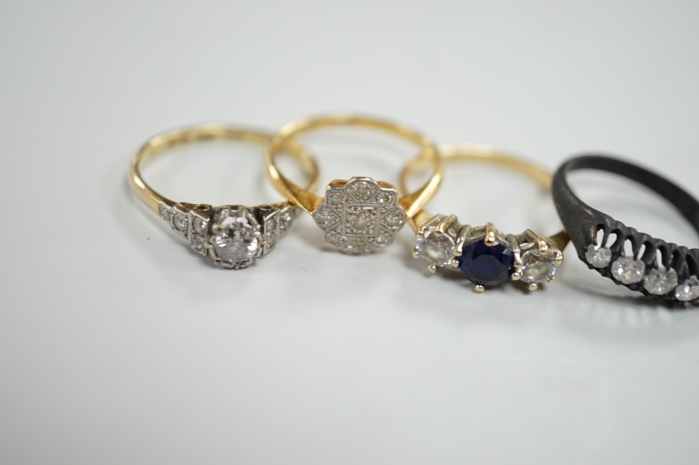 An 18ct, plat and single stone diamond ring, with diamond set shoulders, size O, a similar diamond cluster ring, size N, a blackened? 18ct gold and five stone diamond ring, a late Victorian diamond set heart shaped mourn